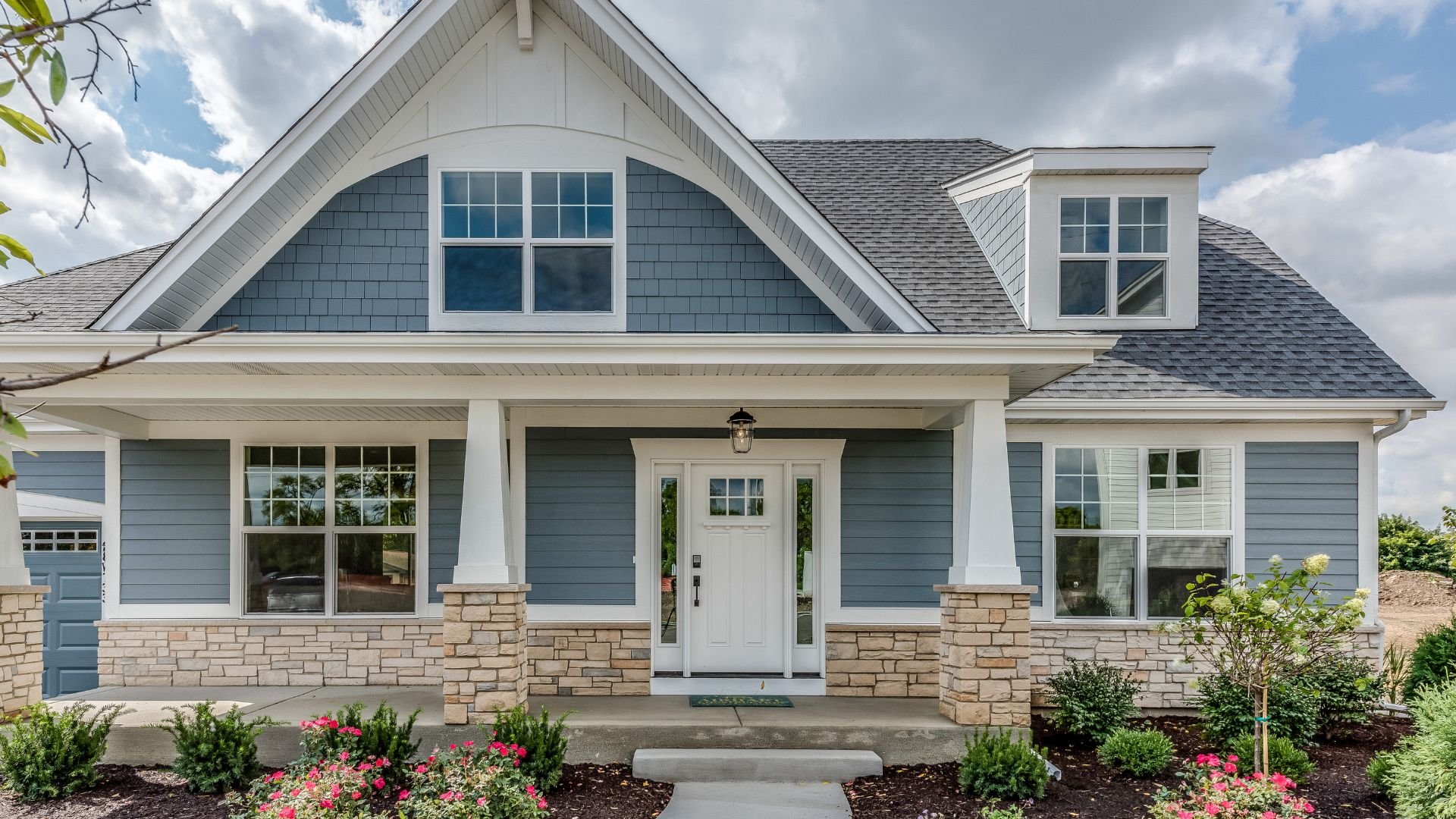 Blue and white craftsman-style house with stone foundation and front porch